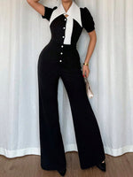 Person wearing a black and white jumpsuit against a white curtain background