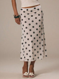 Person wearing a white skirt with black polka dots on a plain background