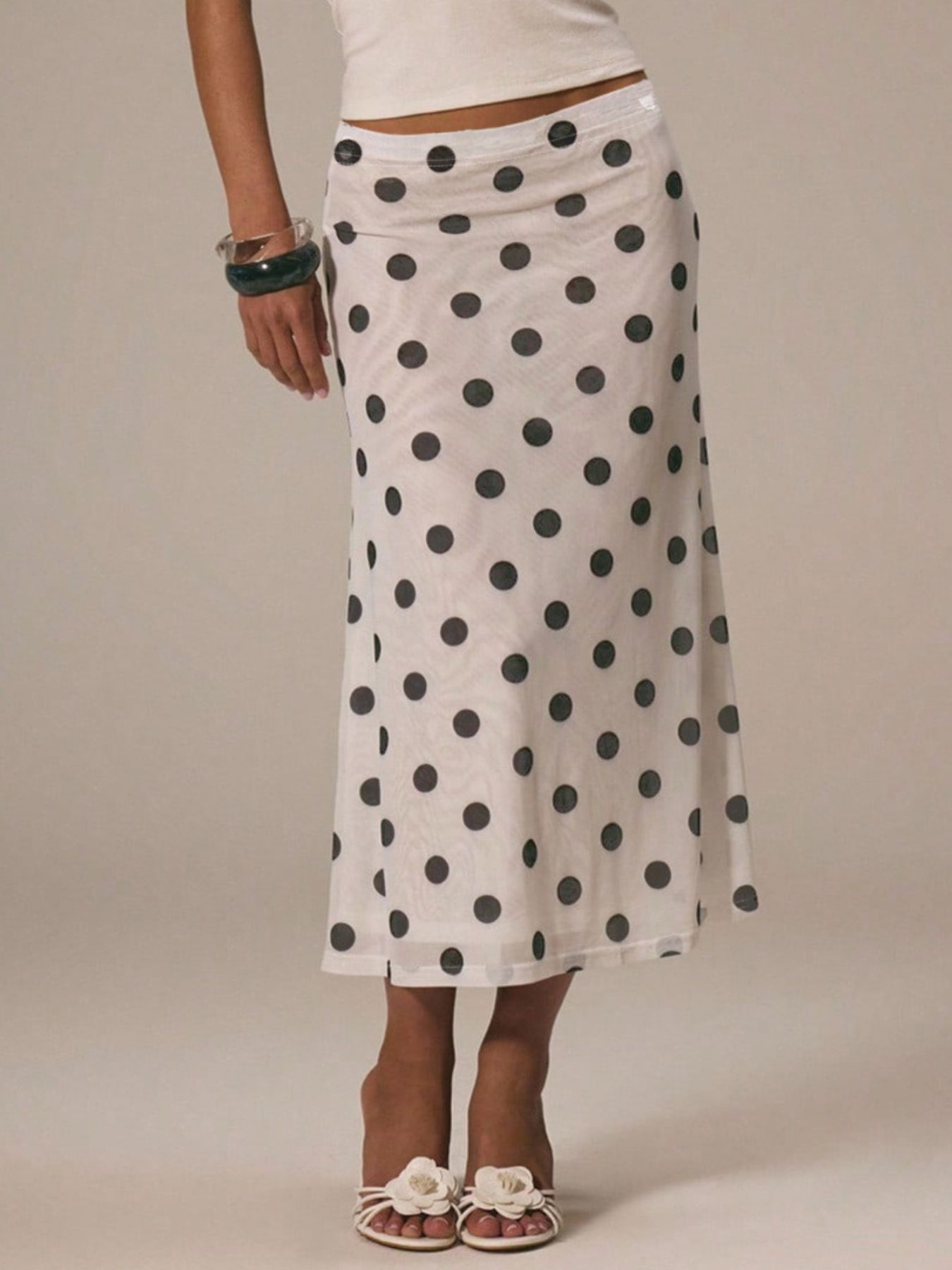Person wearing a white skirt with black polka dots on a plain background