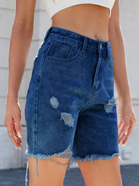 Person wearing blue denim shorts with a blurred background