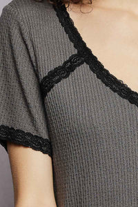 Gray ribbed dress with black lace trim on a neutral background