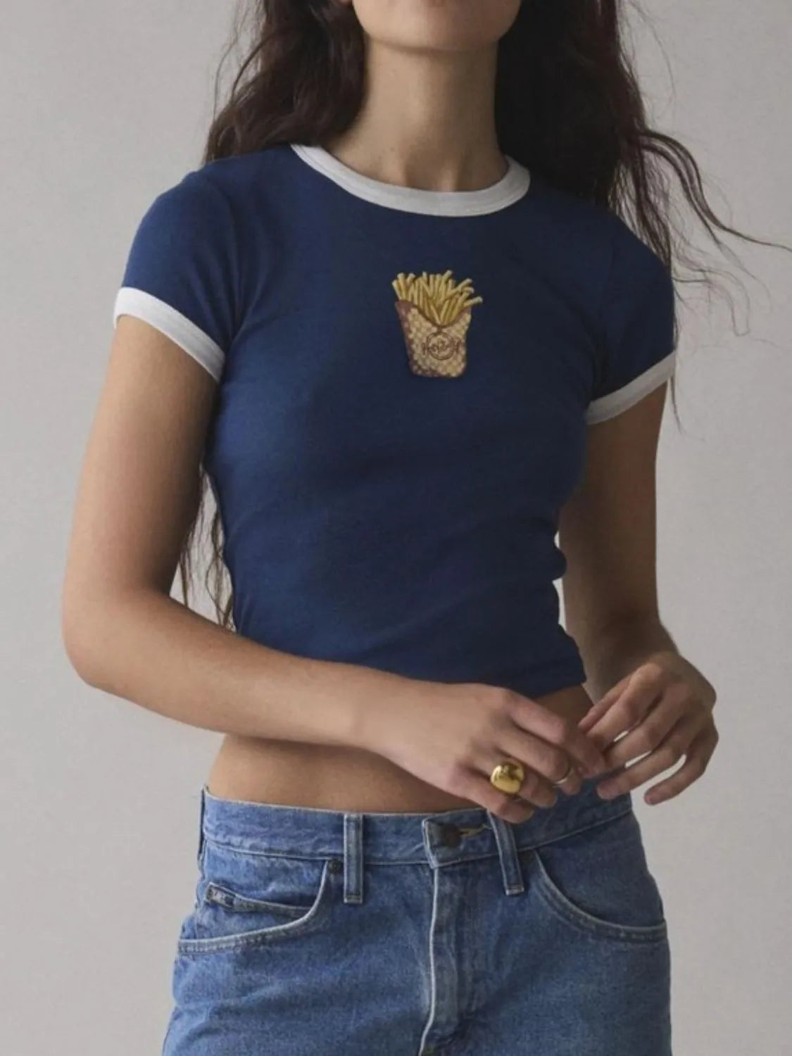 Person wearing a blue t-shirt with a gold graphic design on a plain background