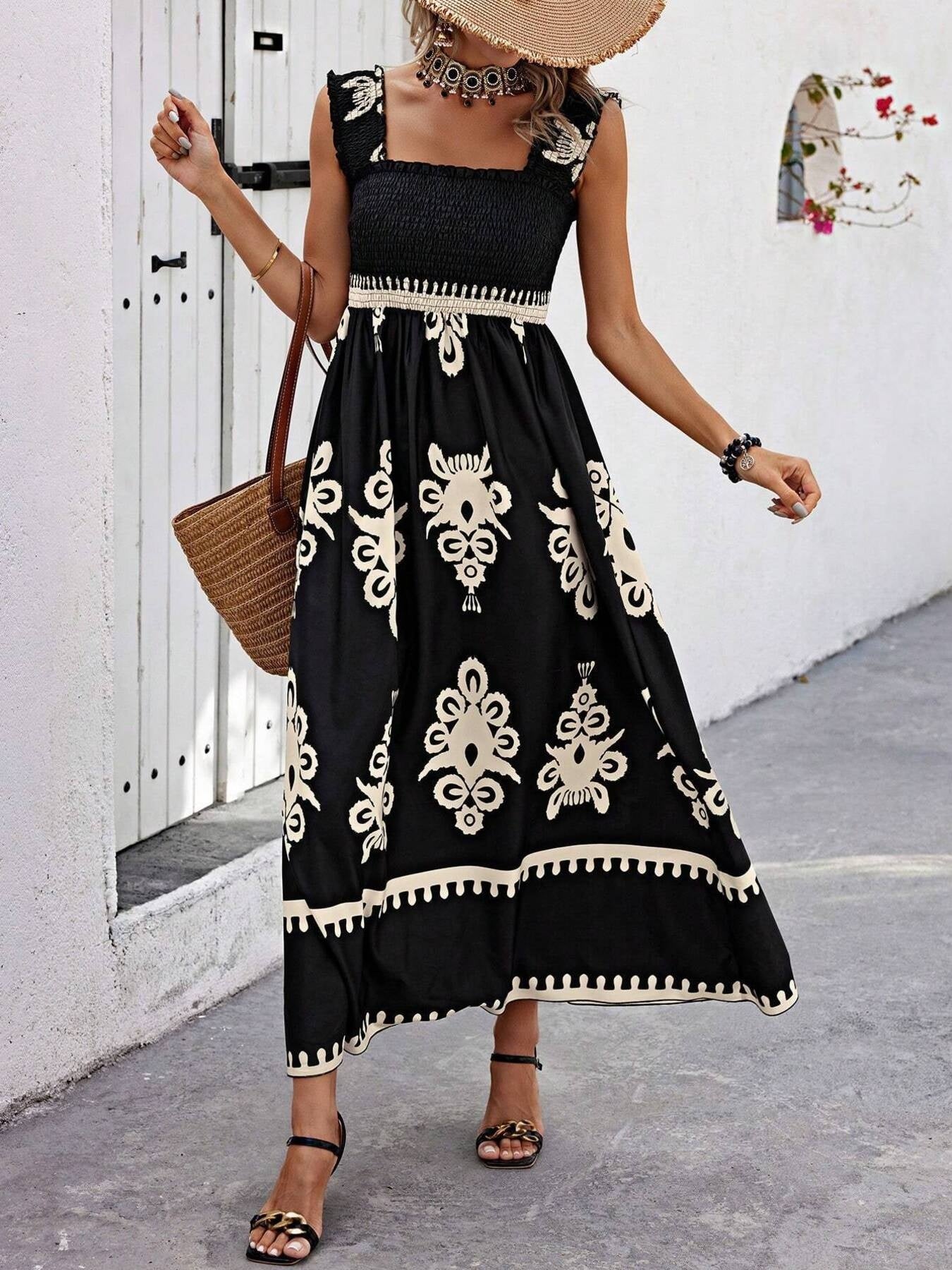 Woman wearing a black dress with white patterns, standing against a white wall.