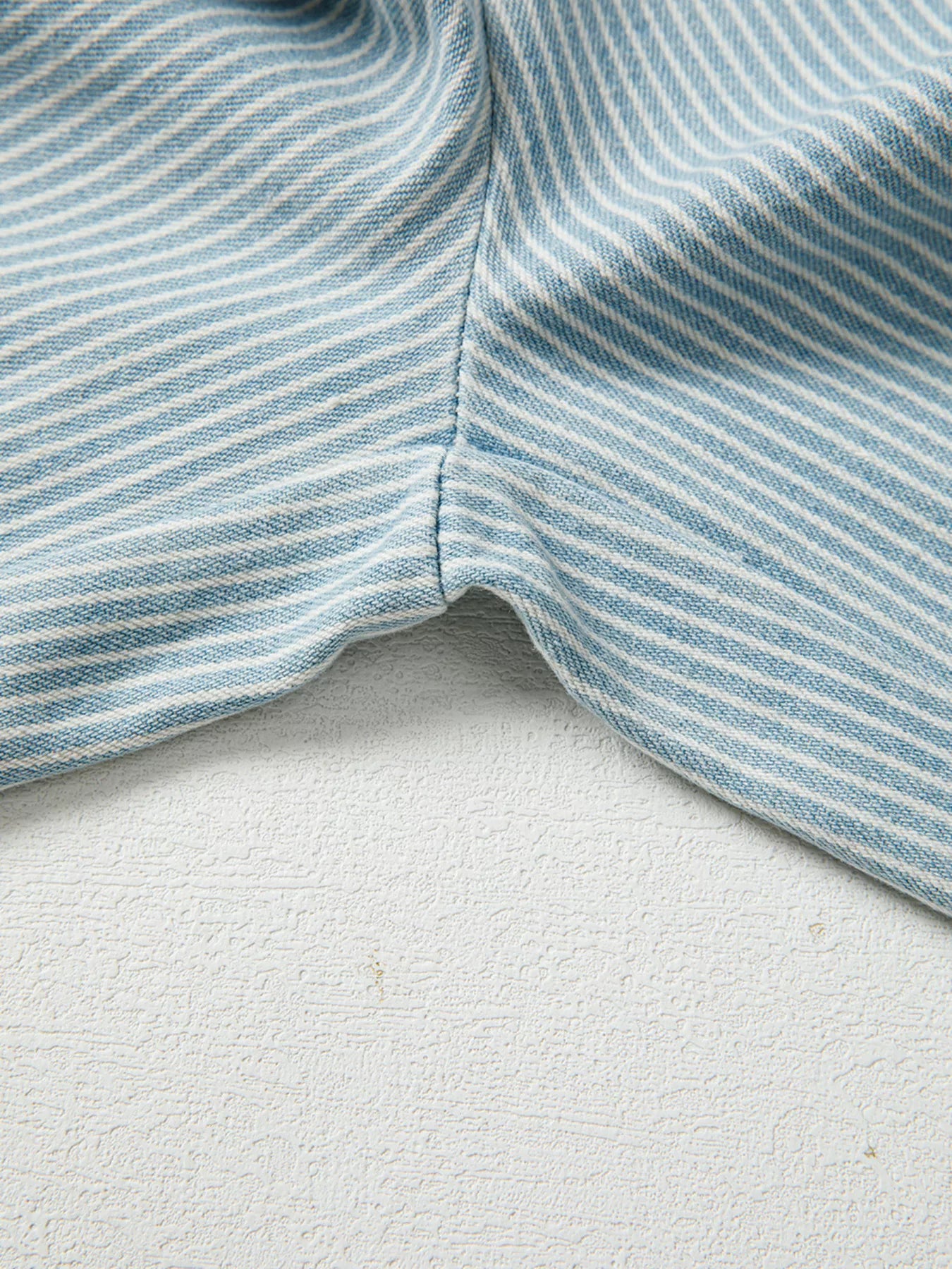 Close-up of blue and white striped fabric on a textured surface