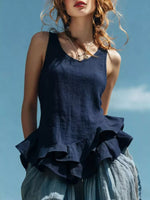 Woman wearing a navy blue ruffled top against a clear blue sky