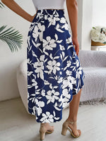 Person wearing a navy blue floral skirt in a room with a bed and plant.