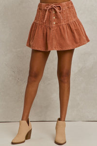 Corduroy skirt with button details worn by a person on a neutral background
