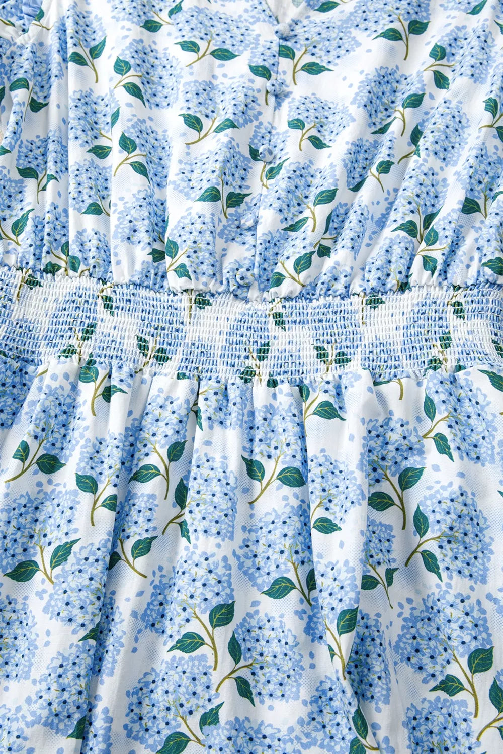 Close-up of a blue floral patterned fabric with green leaves on a white background