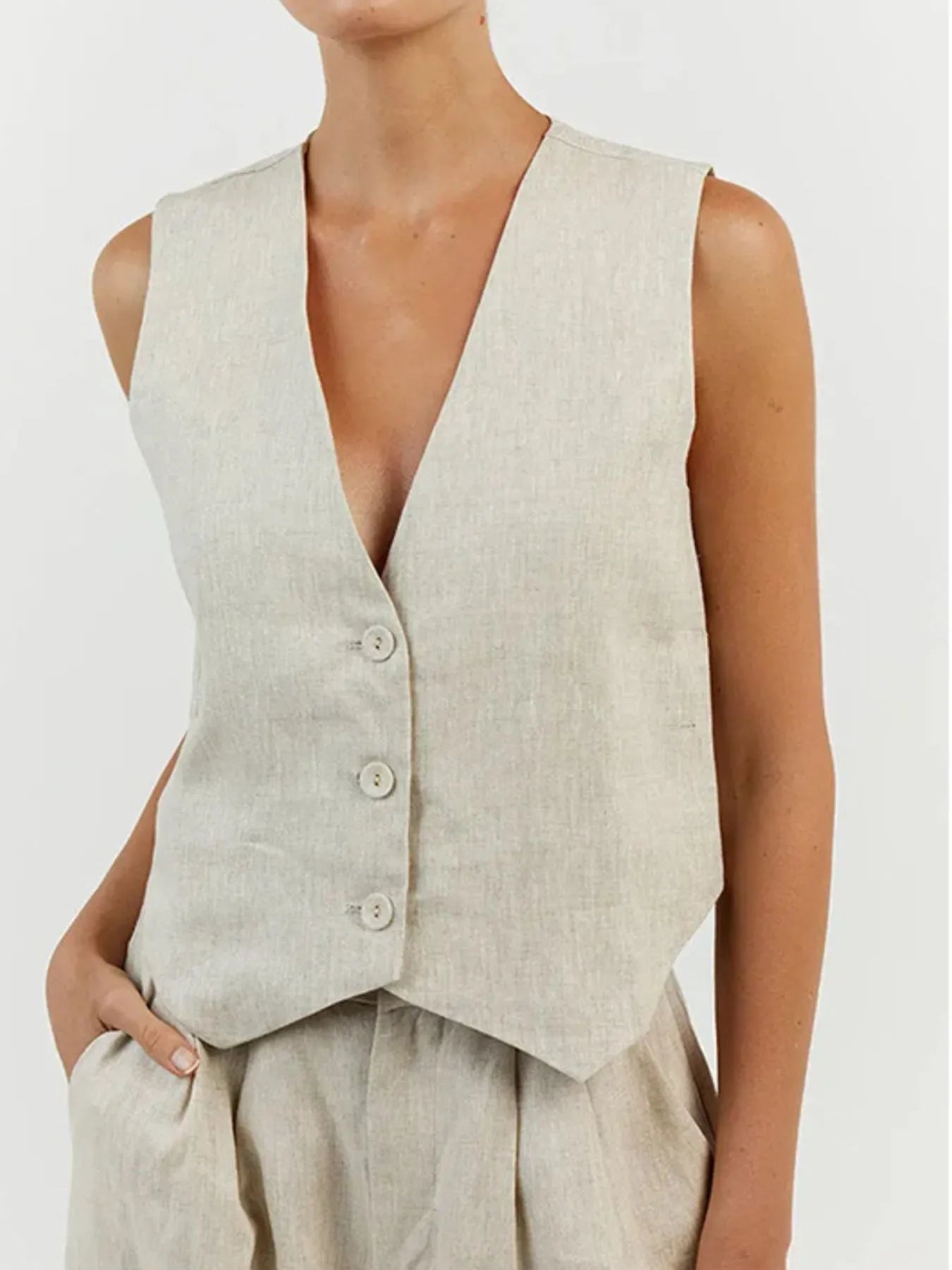 Person wearing a beige vest and pants on a white background