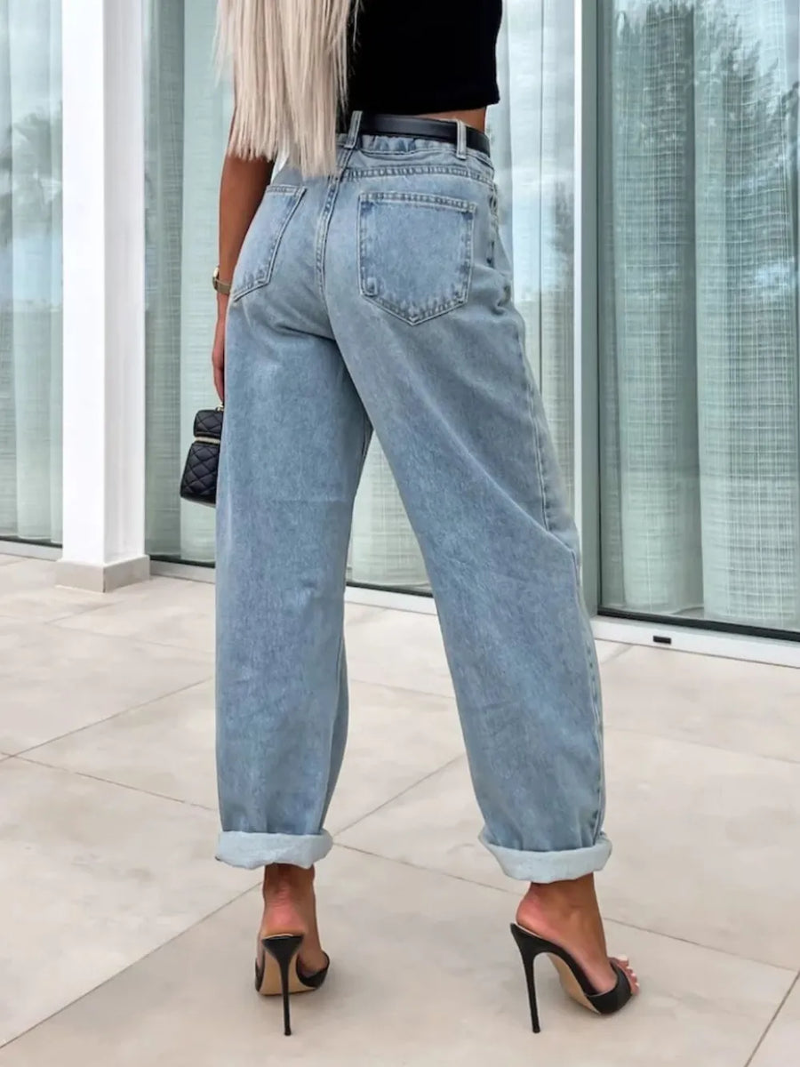 Person wearing light blue jeans and black high-heeled shoes indoors.