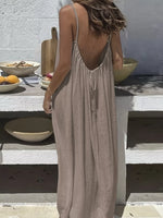 Woman in a beige dress standing on outdoor steps with a rustic setting.