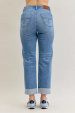 Blue jeans worn by a person on a beige background