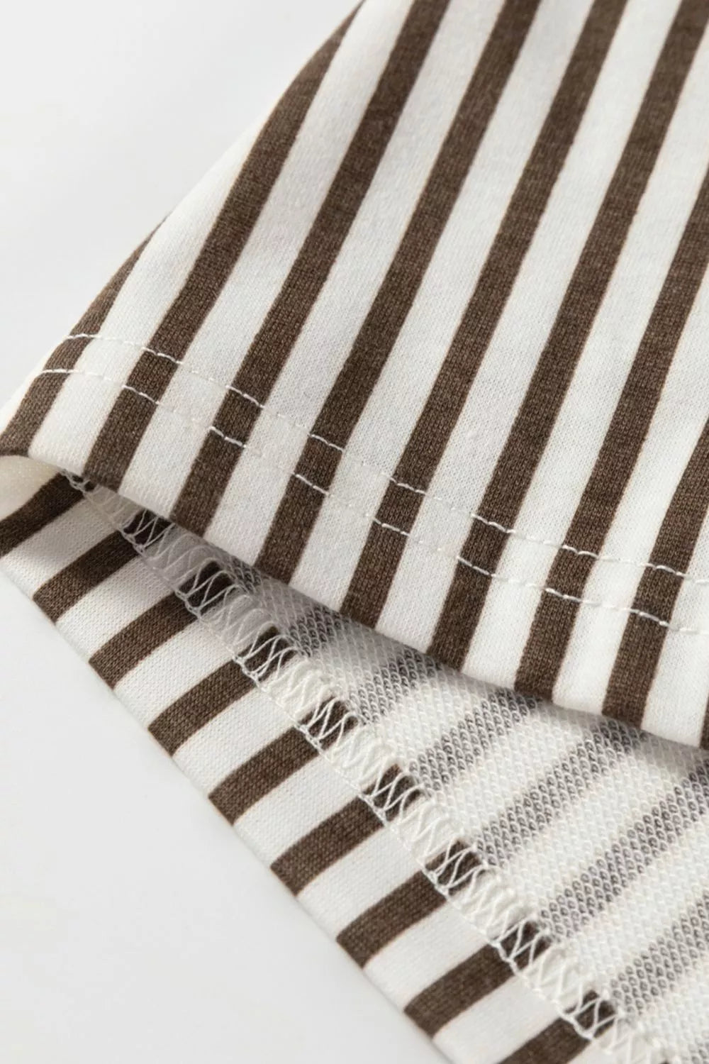 Close-up of a brown and white striped fabric with tassels on a light gray background