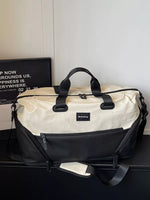 Beige and black duffel bag on a dark surface with a white wall background