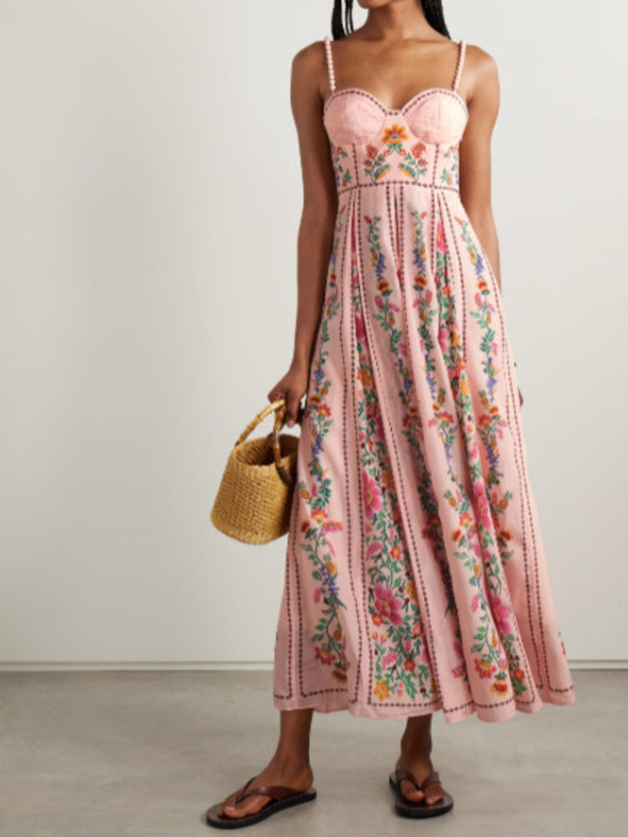 Woman wearing a pink floral dress holding a straw bag against a plain background