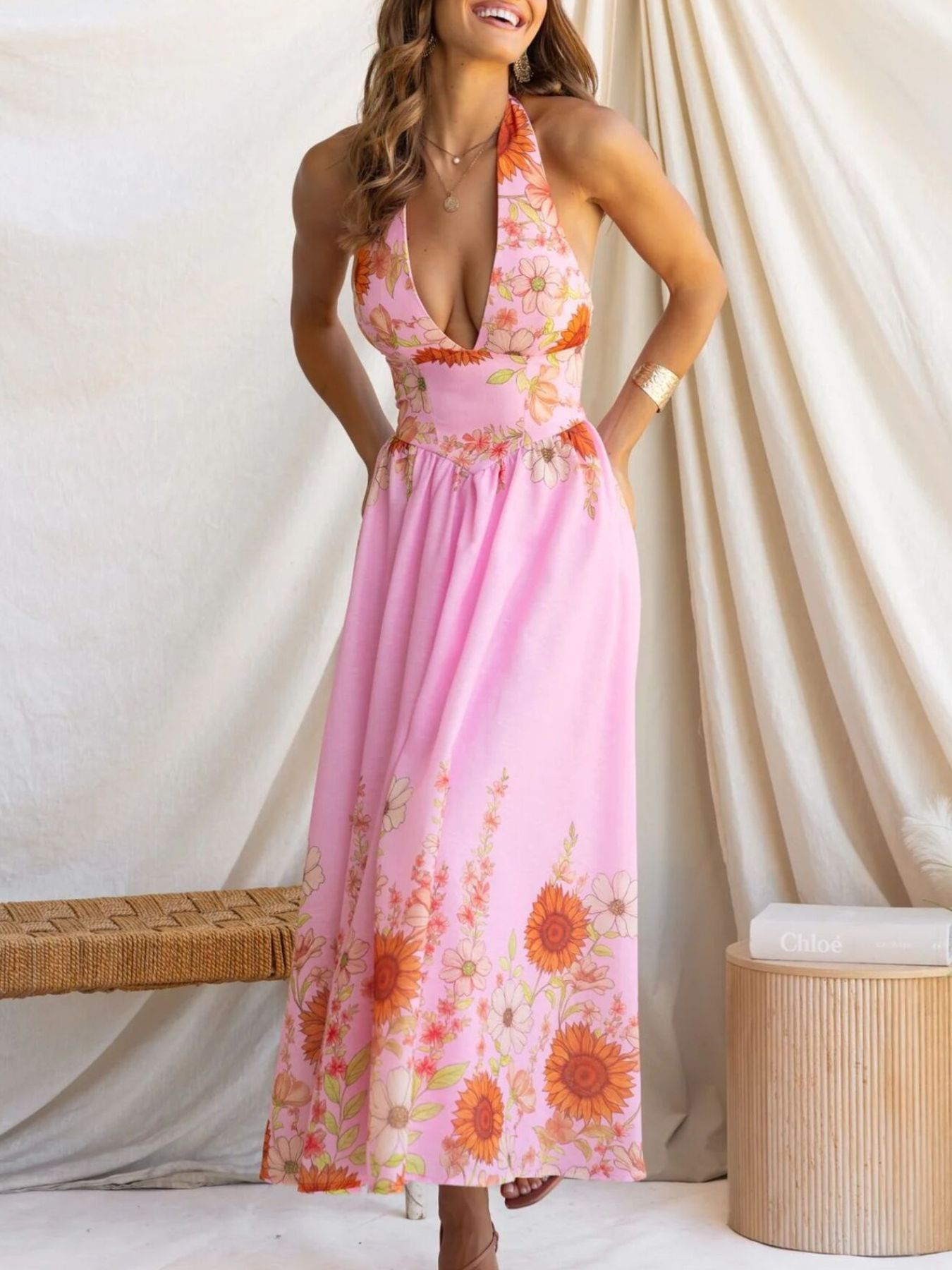 Woman wearing a pink floral dress against a white curtain background