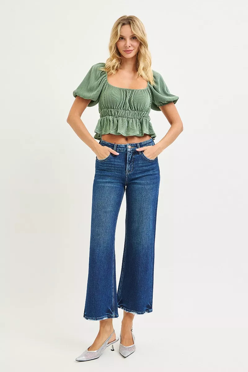 Woman wearing a green top and blue jeans on a white background