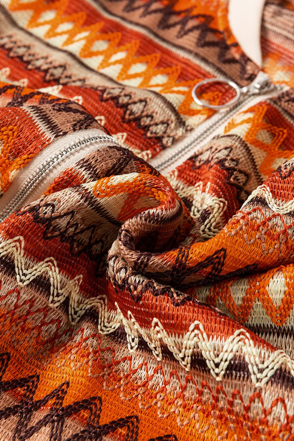 Close-up of a patterned fabric with orange, brown, and beige colors.
