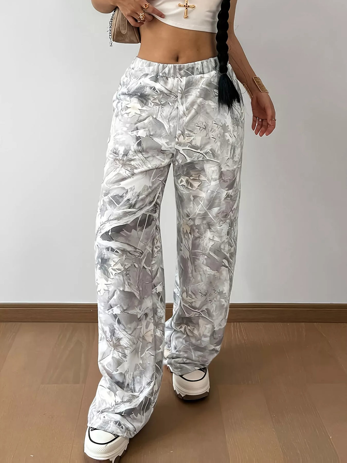 Person wearing white floral pants on a plain background