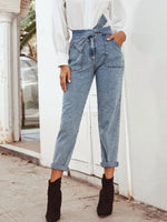 Person wearing high-waisted blue jeans and black ankle boots in an outdoor setting.