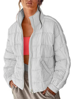 Person wearing a light gray quilted jacket over a pink sports bra and beige pants on a white background