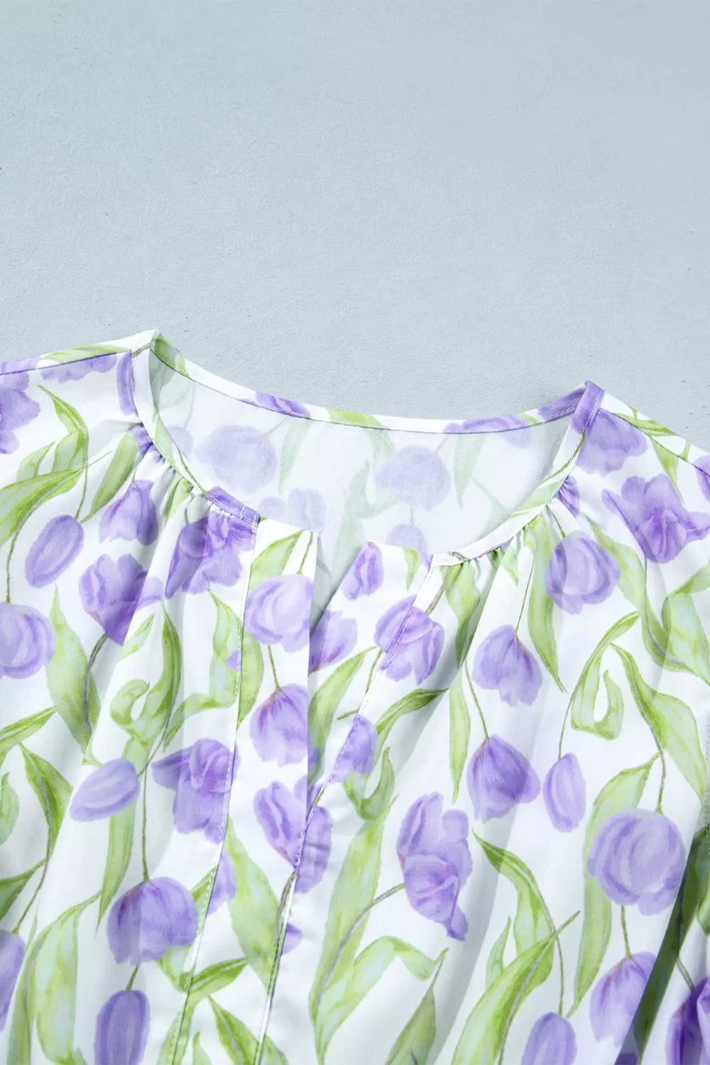 Close-up of a dress with purple floral pattern on a light gray background