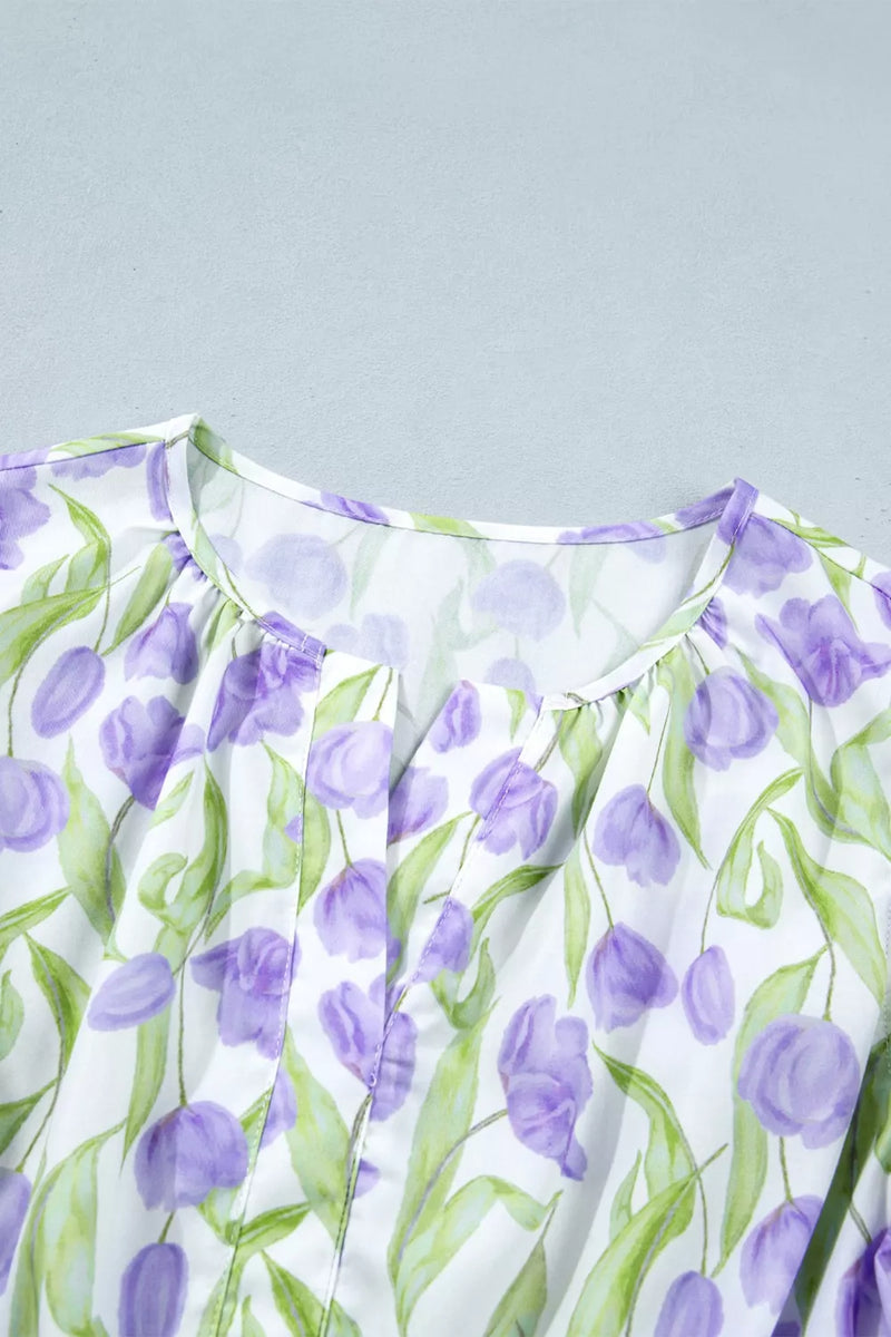 Close-up of a dress with purple floral pattern on a light gray background