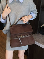 Person holding a brown handbag with a neutral background