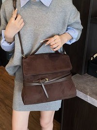 Person holding a brown handbag with a neutral background