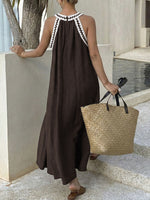 Woman in a brown dress with white trim holding a straw bag by a poolside.