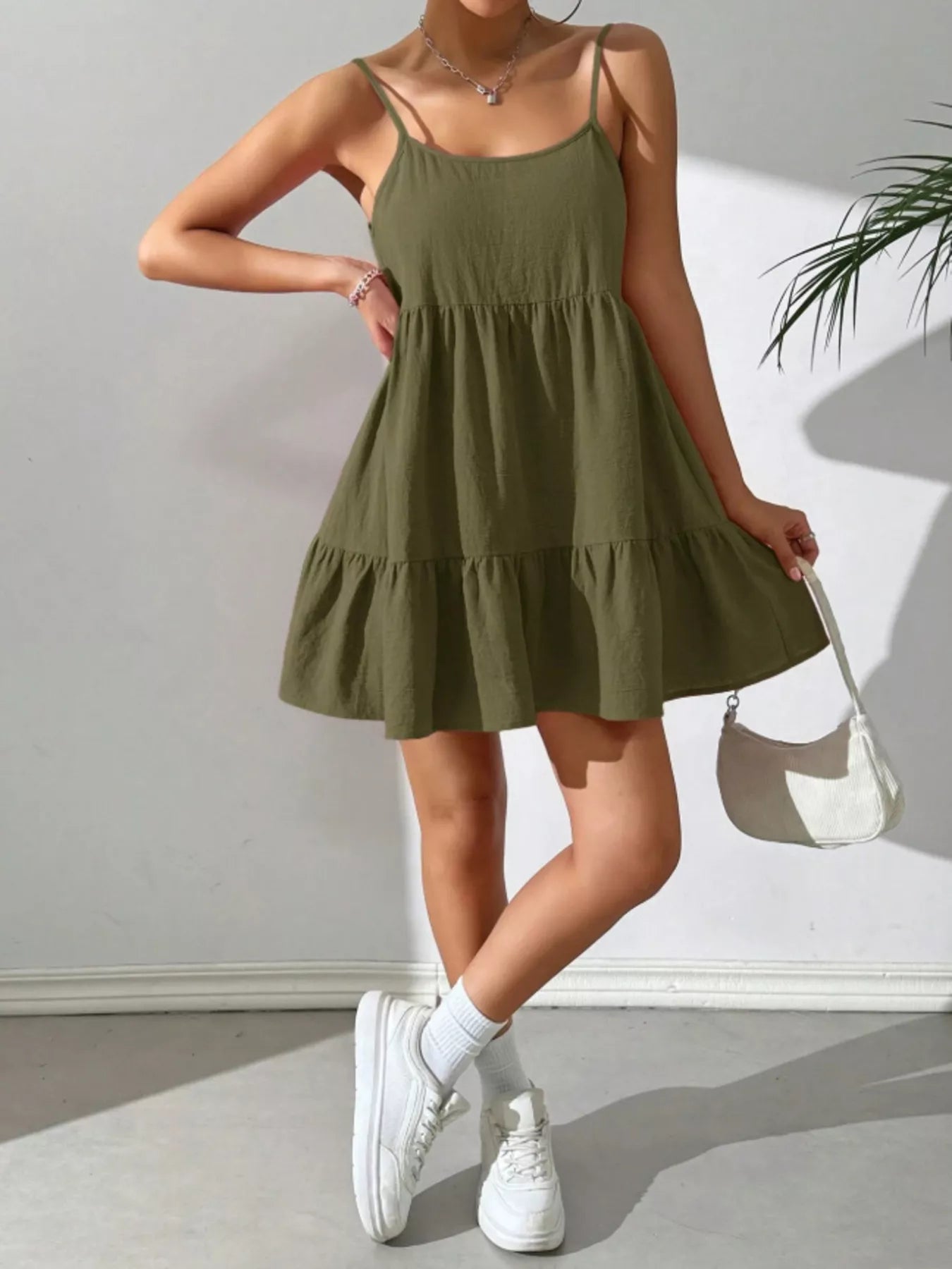 Person wearing a green dress with white sneakers against a plain background