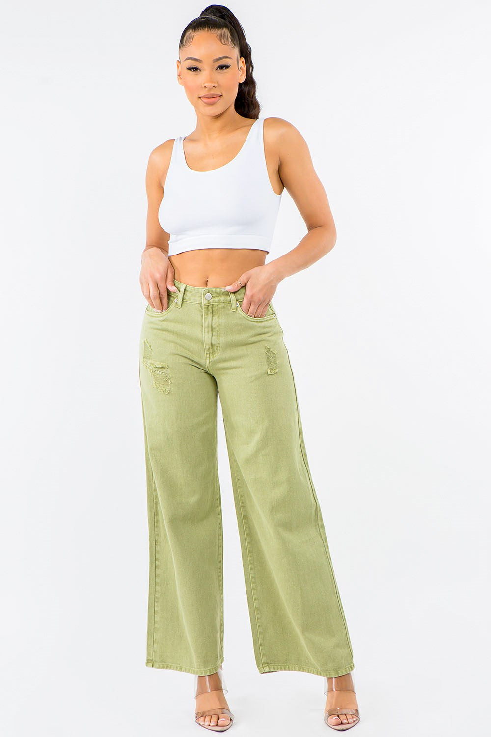 Woman wearing a white crop top and light green wide-leg jeans on a white background