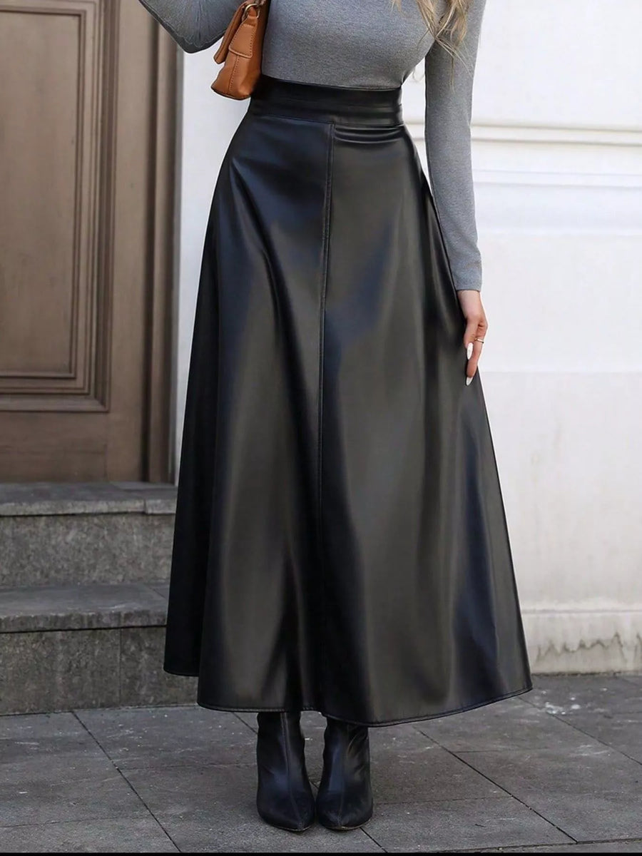 Person wearing a black leather skirt with a gray top and brown shoes.