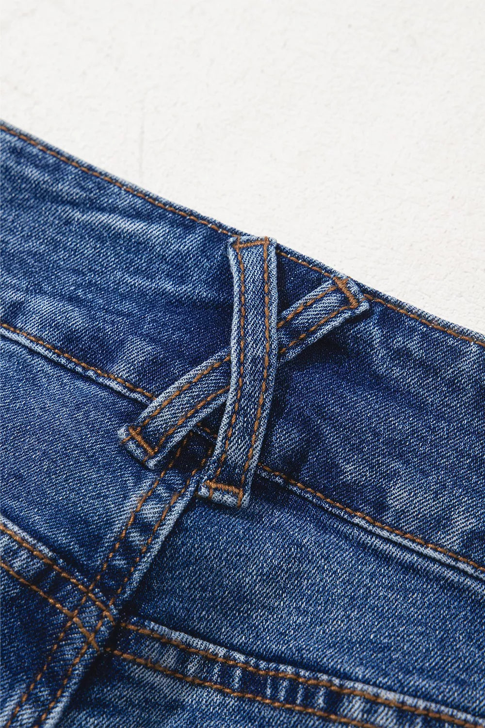 Close-up of blue denim fabric with stitching detail on a white background