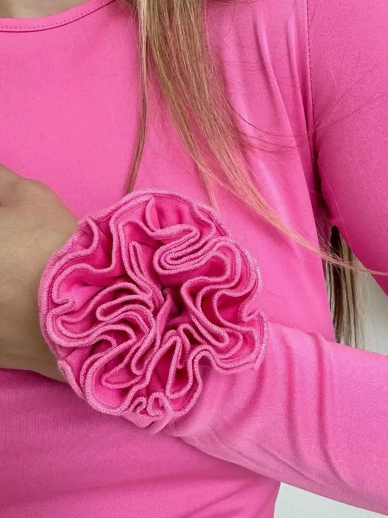 Close-up of a pink long-sleeve top with a ruffled elbow detail.