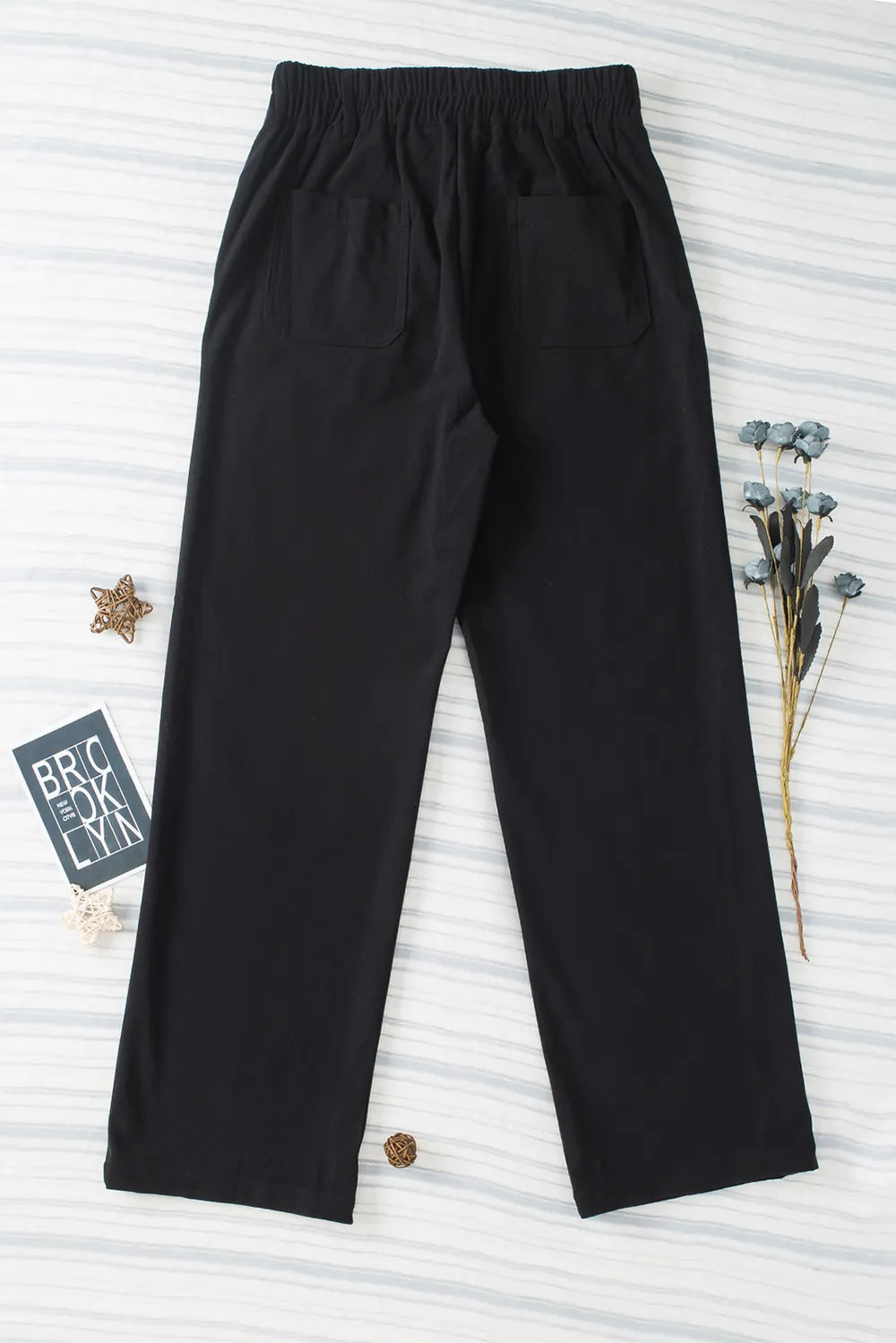 Black pants on a textured white background with decorative elements.