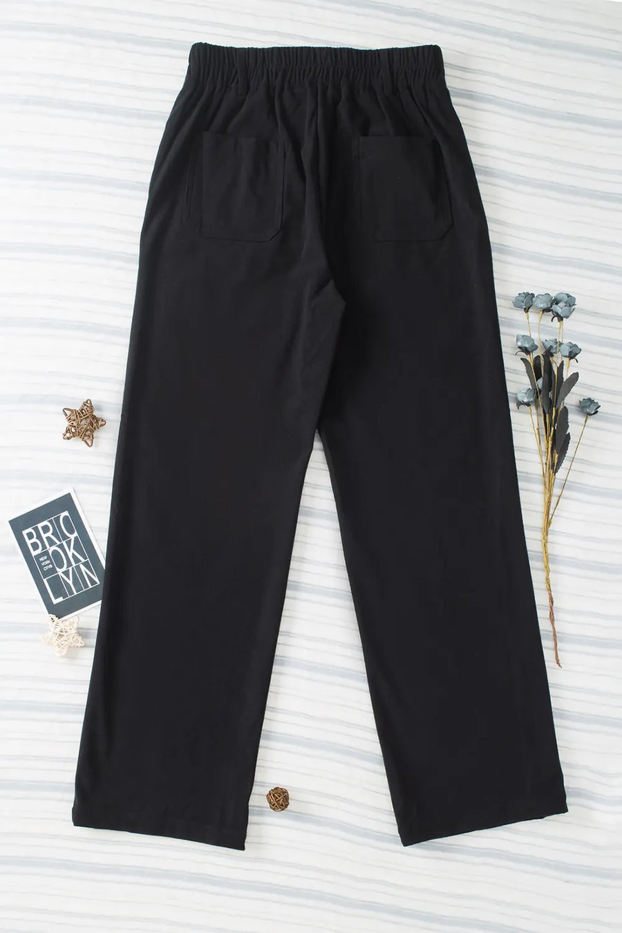 Black pants on a textured white background with decorative elements.
