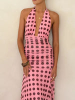 Woman wearing a pink dress with black polka dots against a beige background