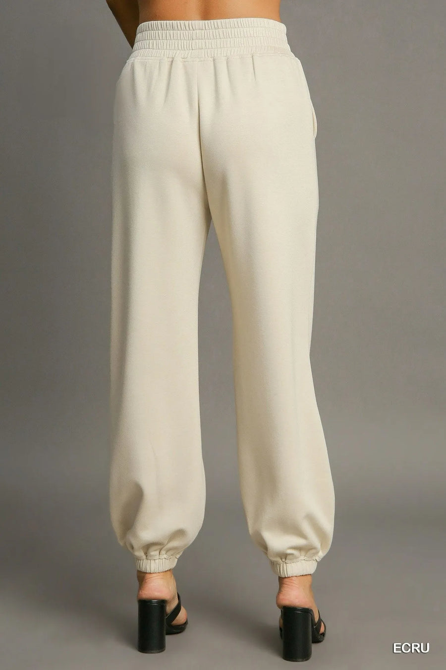 Beige sweatpants on a gray background with 'ECRU' text.