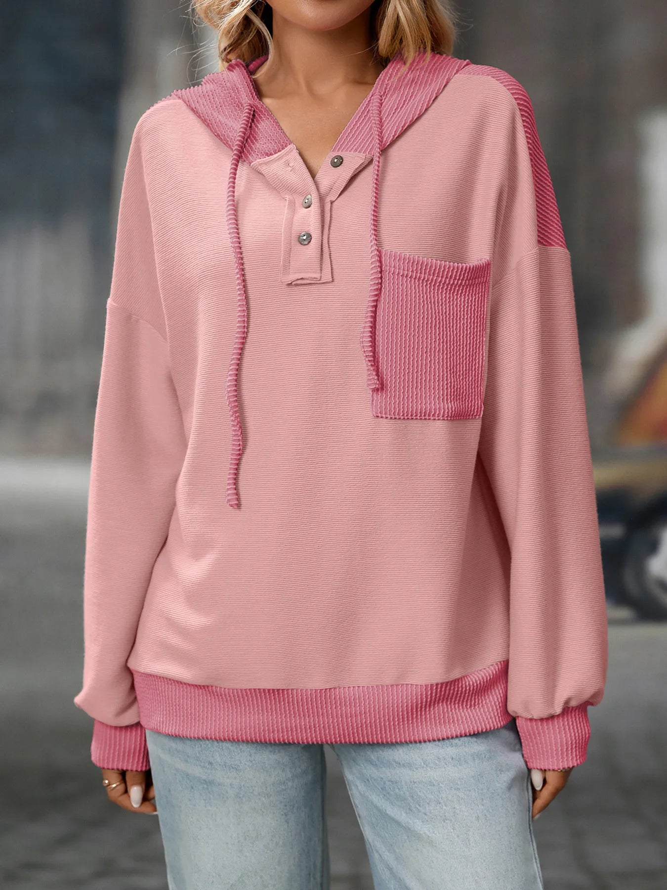 Pink hoodie with a pocket worn by a person, blurred background