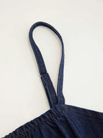 Navy blue denim dress with thin straps on a light gray background