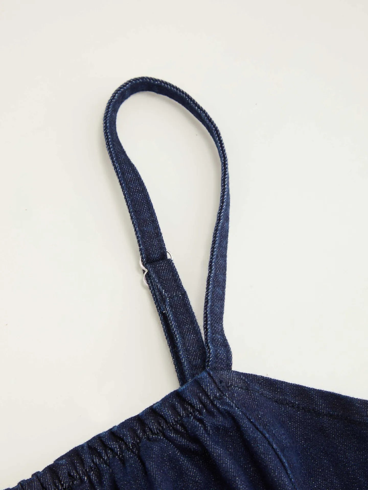 Navy blue denim dress with thin straps on a light gray background