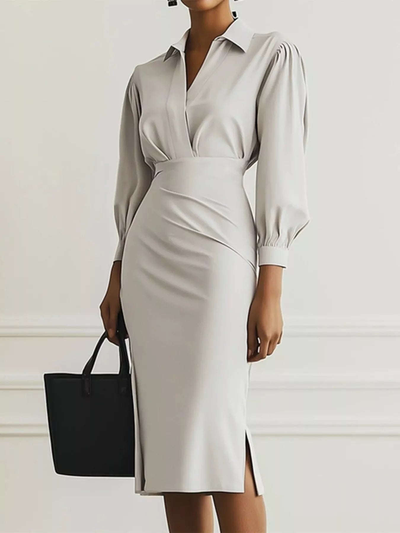 Woman wearing a light gray dress with a black handbag against a white background