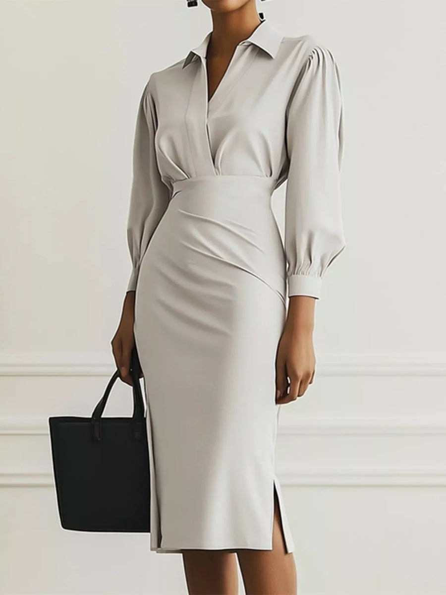 Woman wearing a light gray dress with a black handbag against a white background