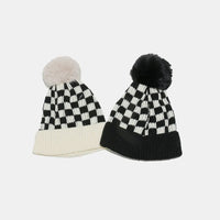 Two checkered beanies with pom-poms on a light gray background
