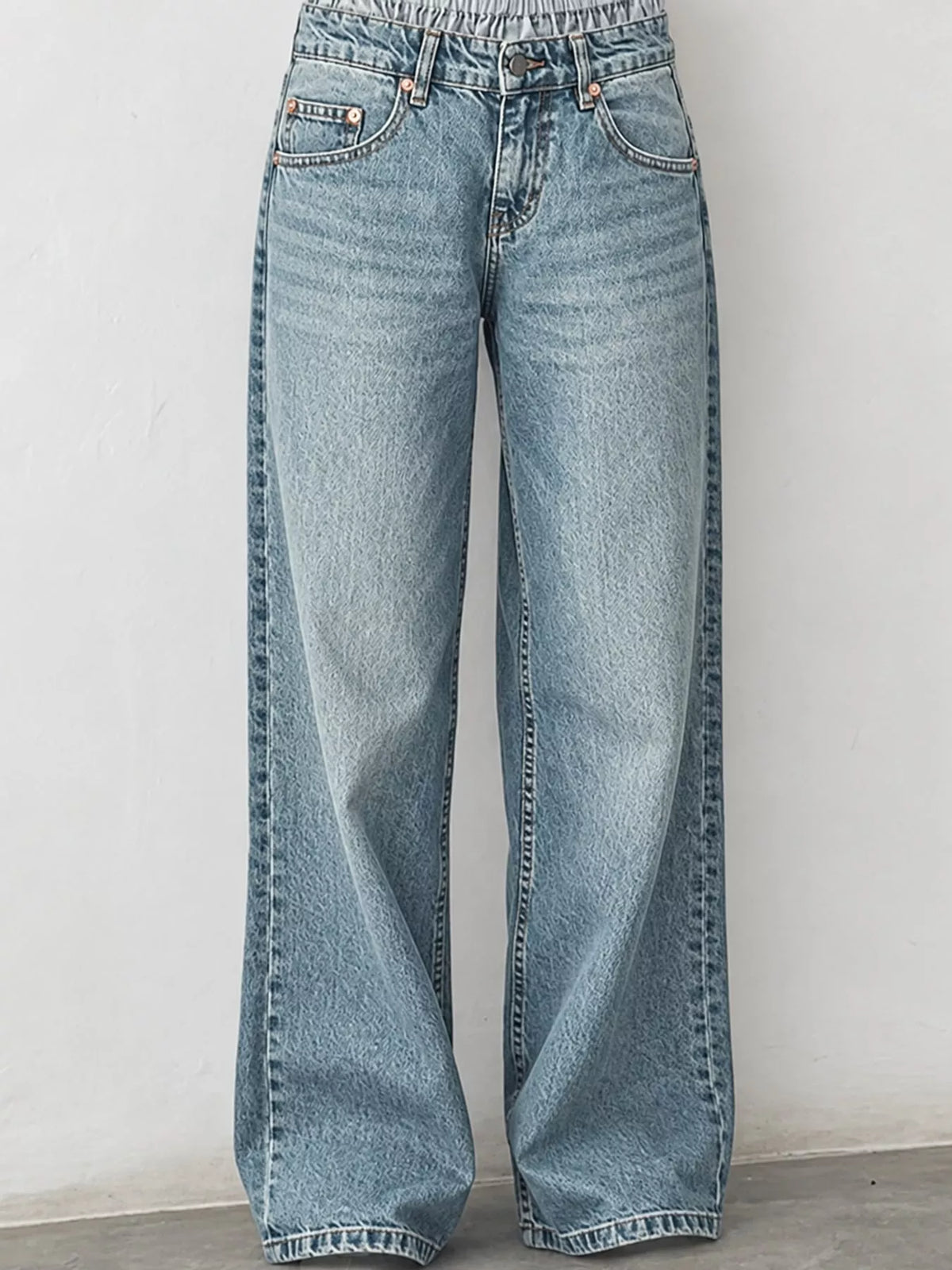 Light blue wide-leg denim jeans with a high waist and elastic waistband, shown against a plain off-white wall.