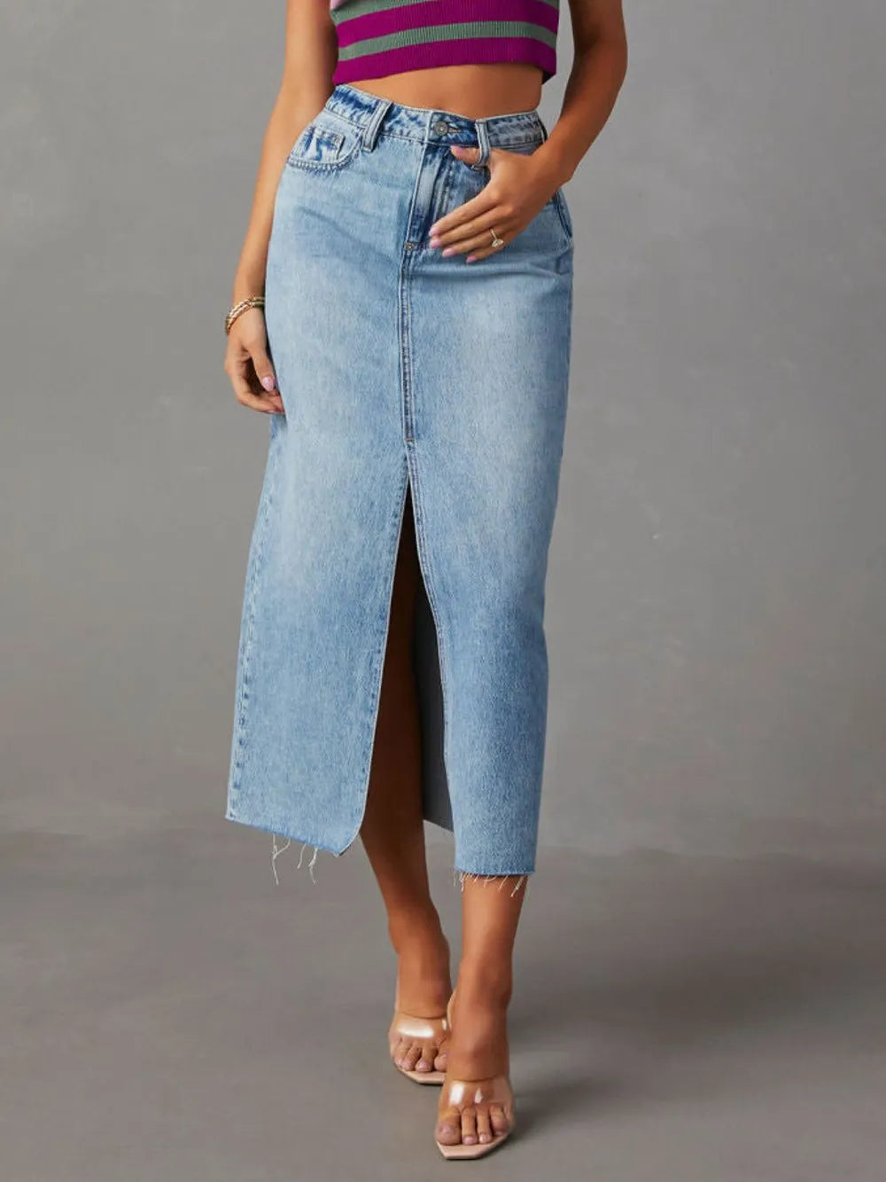 Person wearing a striped crop top and denim skirt on a gray background