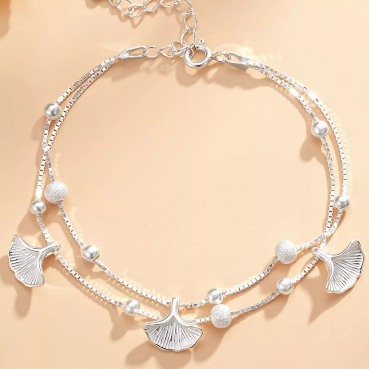 Silver necklace with leaf-shaped pendants on a beige background