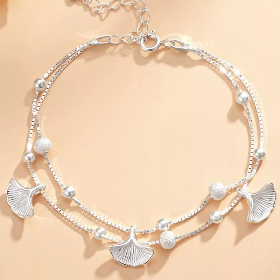 Silver necklace with leaf-shaped pendants on a beige background
