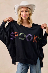 Person wearing a black sweatshirt with colorful 'SPOKES' text, holding it up.
